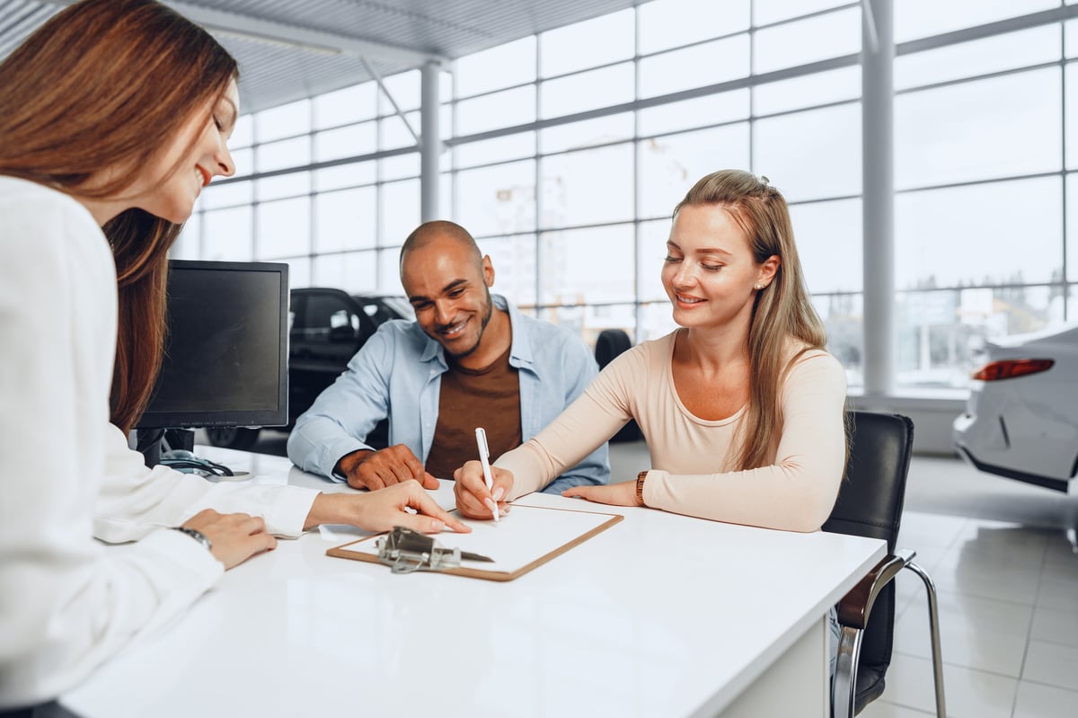 Person signing documents at car dealership