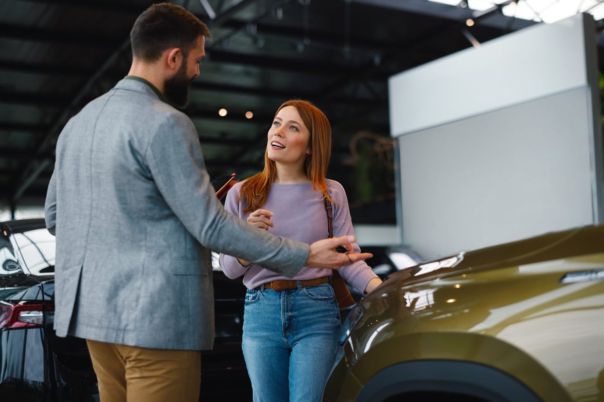 Woman discussing car features with sales consultant at dealership