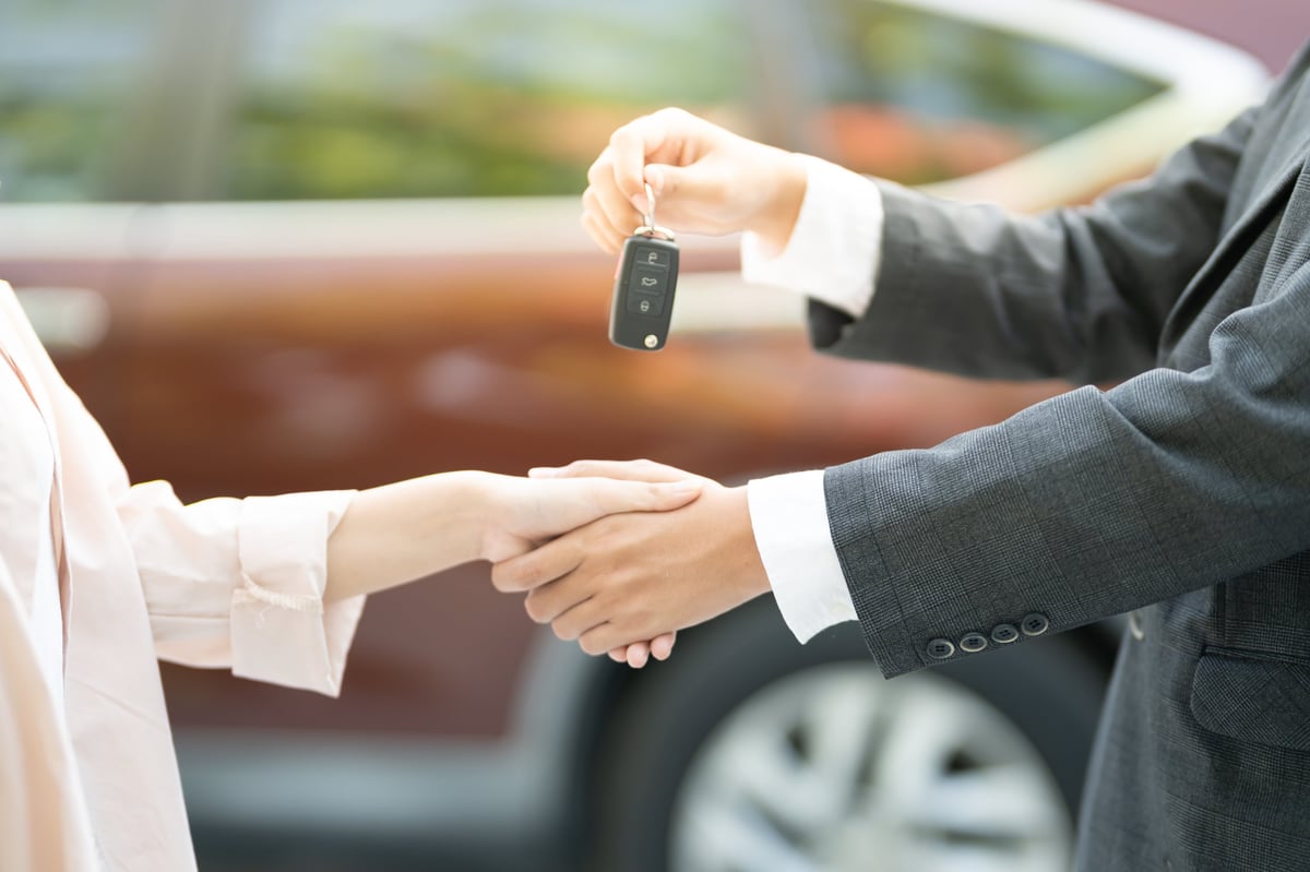 Dealership manager handing car keys to new owner, car trade-in and vehicle purchase transaction concept